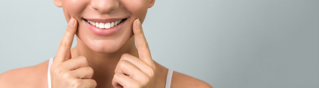 close up a beautiful healthy smile of a young woman on light blue background with copyspace.
